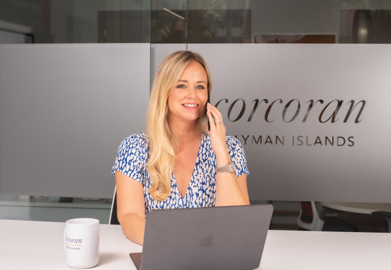 marta-goss-corcoran-cayman-islands-real-estate-agent-smiling-at-desk